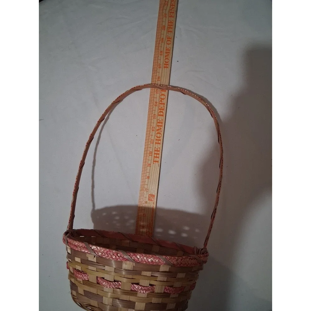 Two vintage woven bamboo baskets with tall‎ handles and pink accenting.